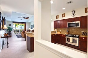 A modern kitchen with dark wood cabinets, stainless steel appliances, and a granite countertop. - Fairway Villas Waikoloa | Golf Course View 2 BR | Free Car w/ 6+ Nts | FVW-L32 (Waikoloa Village)