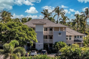 A multi-story residential building with a balcony on the second floor, surrounded by lush greenery and palm trees. - Fairway Villas Waikoloa | 2 BR, Sleeps 6 | Car Incl. w/ 6+ Nights | FVW-L32 by KBM (Waikoloa Village)