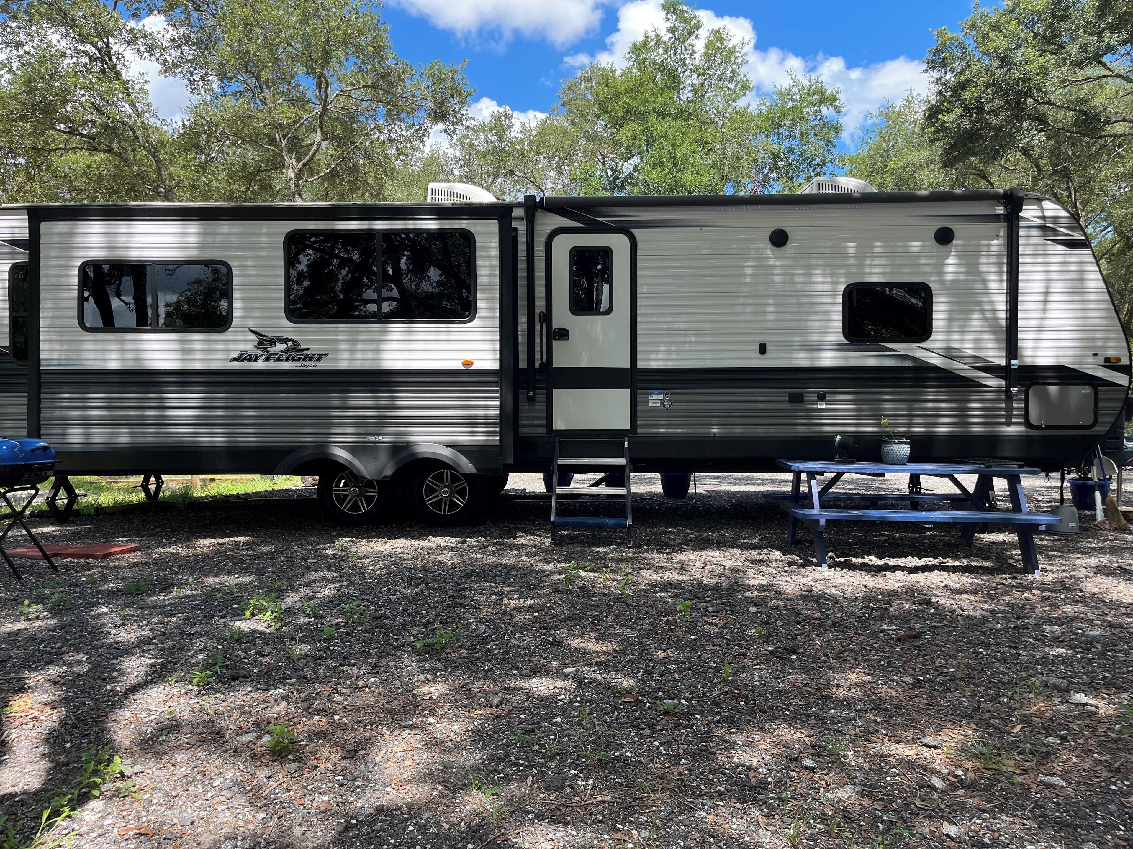 A Jayco Jayco RV parked at a campsite with a picnic table and a small garden area.