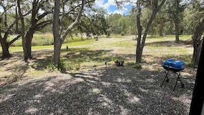 A natural outdoor area with trees, a barbecue grill, and a gravel path. - Cozy 1-bedroom mobile home in beautiful Spring Hill with AC (Spring Hill)