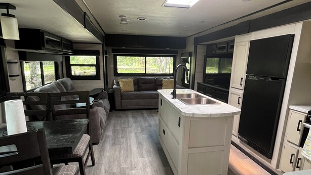 A compact RV kitchen with a dining area, a sink, and a refrigerator. - Cozy 1-bedroom mobile home in beautiful Spring Hill with AC (Spring Hill)