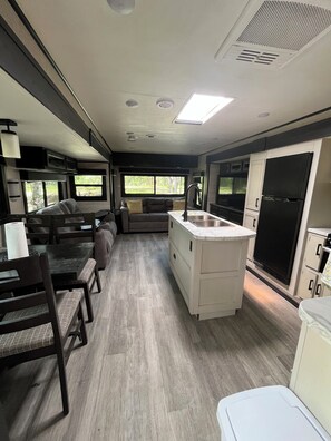 Une cuisine compacte pour camping-car, comprenant un coin repas, un évier et un réfrigérateur.