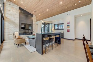 A modern kitchen with a central island, bar stools, and a large window.