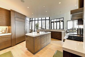 A modern kitchen with a large island, wooden cabinets, and a built-in stove.