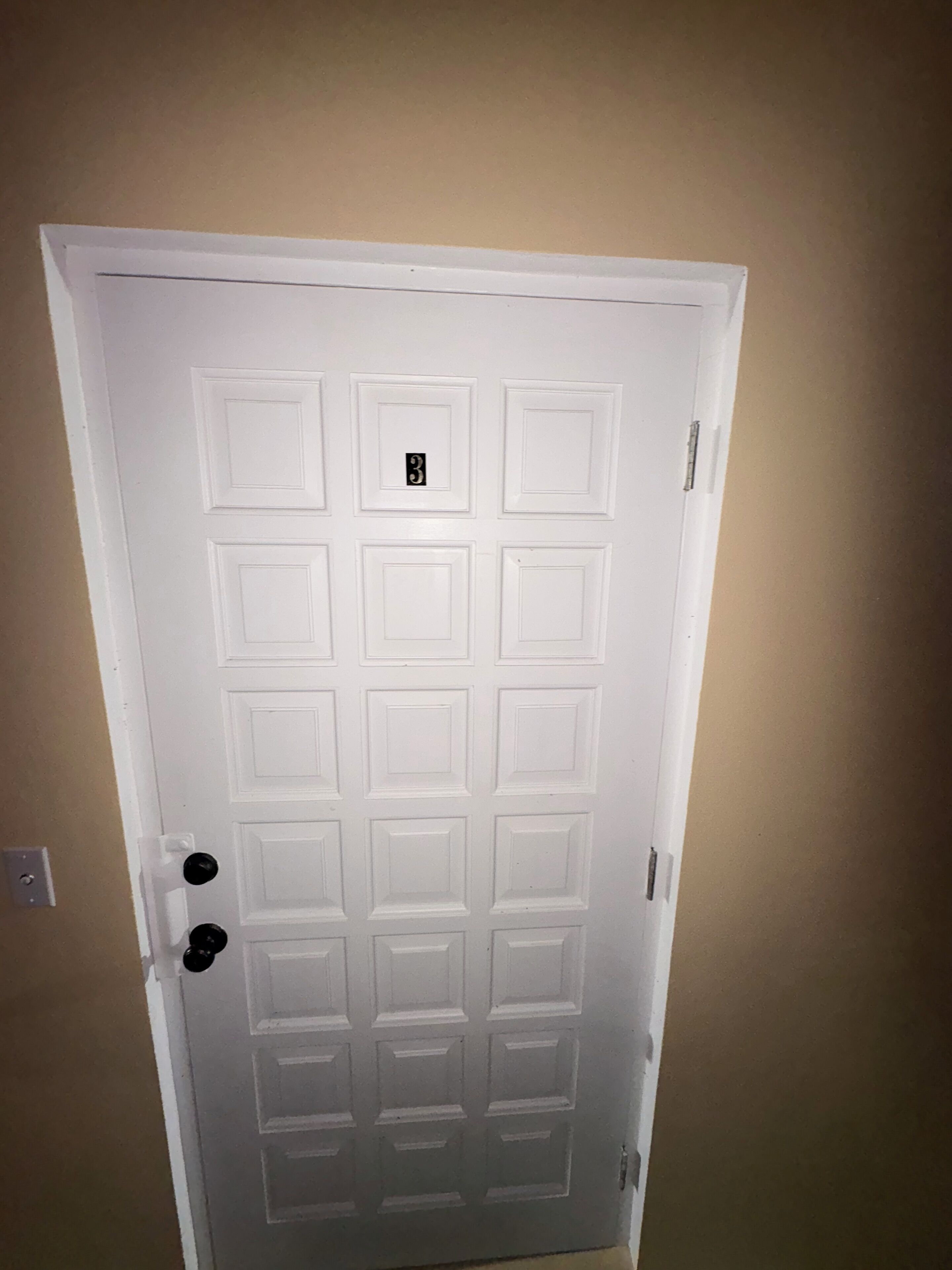 A white door with a numeric keypad lock and a keyhole.