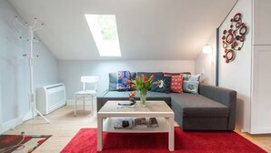 Een moderne woonkamer met een grijze bank, een witte salontafel en een rood vloerkleed.