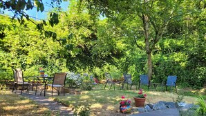 Een terras buiten met een stenen bank, een tafel en stoelen.