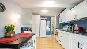 Een compacte keuken met witte kastjes, een zwart aanrecht en een eethoek met een tafel en stoelen.