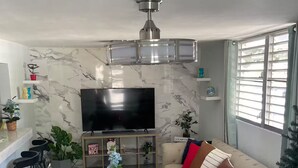 A living room with a sofa, a coffee table, a TV, and a ceiling fan.