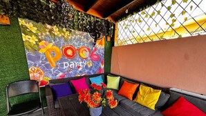 An outdoor seating area with a sofa, chairs, and a table. A mural with the word "party" is visible on the wall.