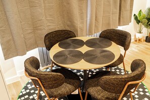 A round table with a woven placemat, surrounded by four wicker chairs with wooden legs. - Luxury 2-Bedroom Apartment on Iconic Baker Street | Central London (London)