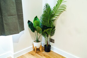 A corner with a wooden floor, a white wall, and two potted plants. - Luxury 2-Bedroom Apartment on Iconic Baker Street | Central London (London)