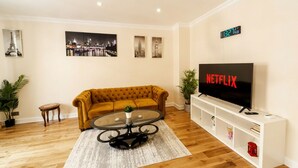 A living room with a sofa, coffee table, TV, and wall art. - Luxury 2-Bedroom Apartment on Iconic Baker Street | Central London (London)