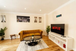 A living room with a sofa, coffee table, TV, and wall art. - Luxury 2-Bedroom Apartment on Iconic Baker Street | Central London (London)
