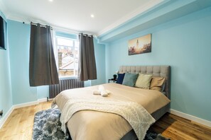A bedroom with a bed, curtains, a window, and a painting on the wall. - Luxury 2-Bedroom Apartment on Iconic Baker Street | Central London (London)