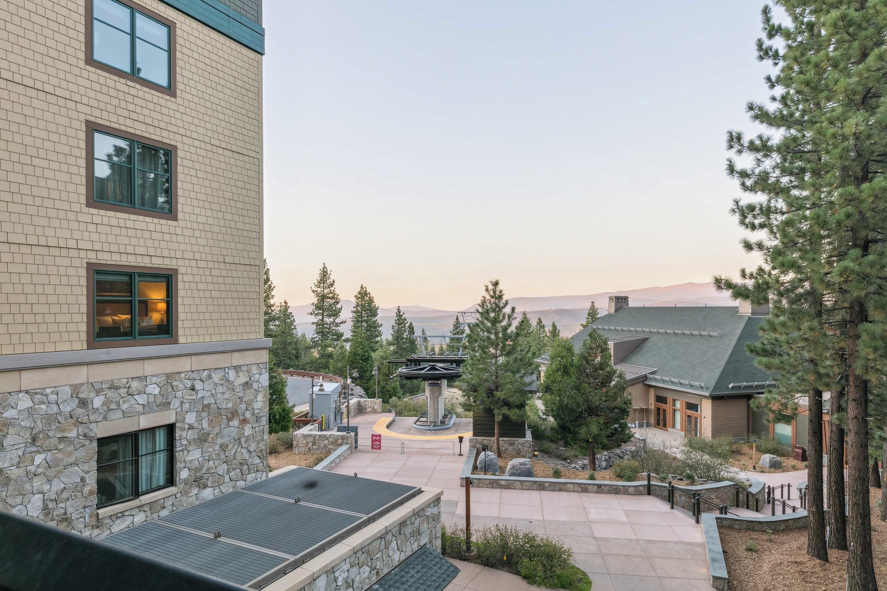 A building with a stone facade, a rooftop terrace, and a courtyard with trees and a central structure.