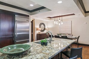 A modern kitchen with a stainless steel refrigerator, granite countertops, and pendant lighting. - Northstar Resort Mid-Mountain Ski in/Ski in/Ski out 3 bedroom condo (Truckee)
