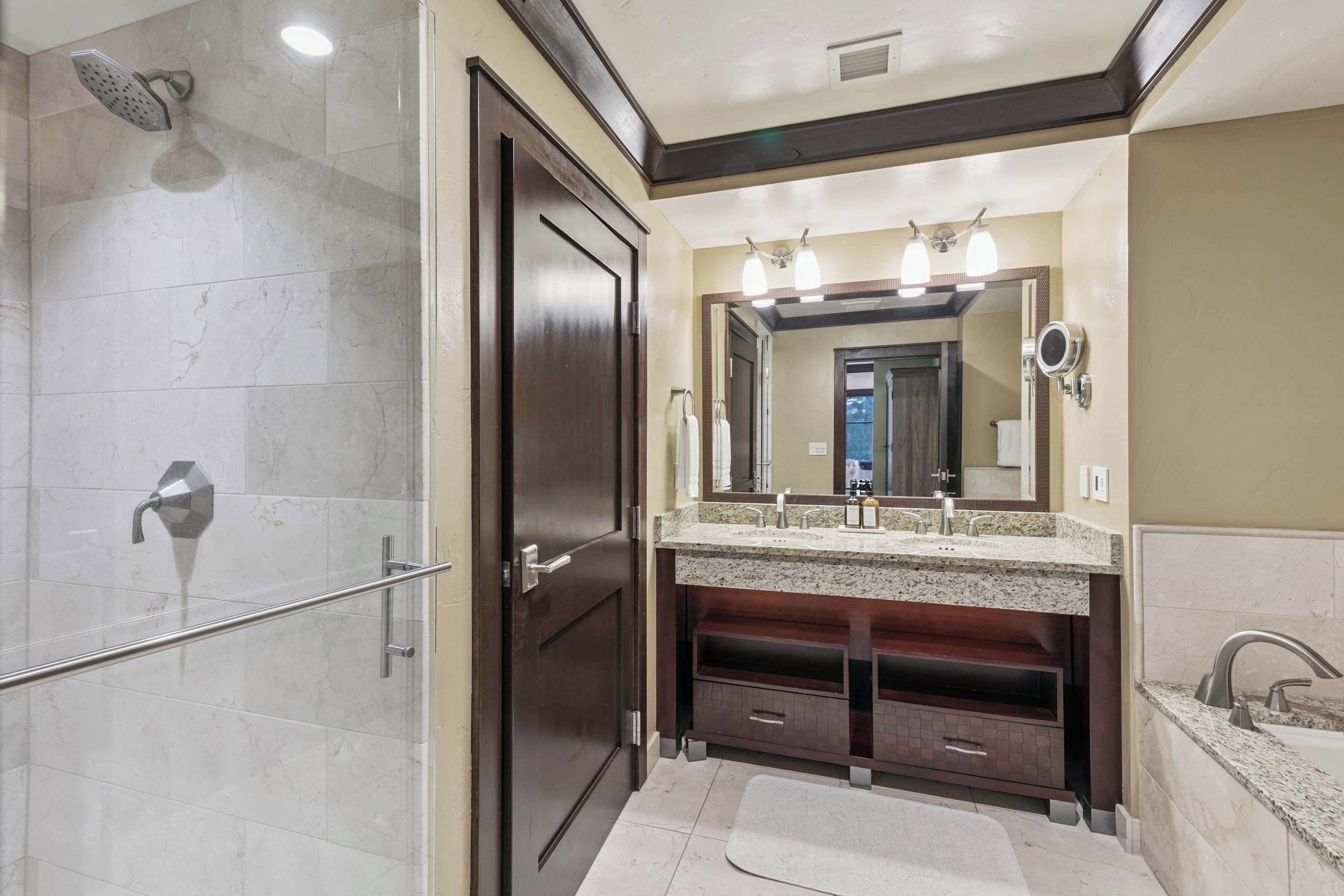 A bathroom with a shower, a vanity with a mirror, and a sink.