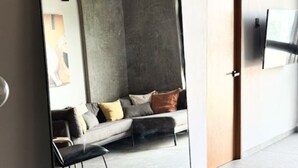 A modern interior with a large mirror reflecting a living area, a sofa, and a television. - Upscale 2BR/2BA Apartment with Incredible Mountain Views (Oaxaca de Juárez)