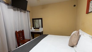 A hotel room with a bed, a chair, a desk, a mirror, and a television. - Hotel Maria Bonita (Tequila)