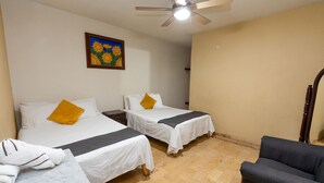 A hotel room with two beds, a ceiling fan, a painting, and a chair. - Hotel Maria Bonita (Tequila)