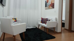 Una sala de estar moderna con dos sofás blancos, un tapete mullido negro y un cuadro en la pared.