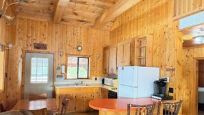 Ein Holzblockhaus mit Essbereich, Küche und einer Uhr an der Wand.