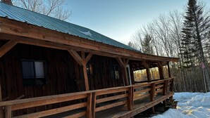 Una cabana de fusta amb un porxo cobert i terra coberta de neu.