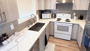Een moderne keuken met witte kastjes, roestvrijstalen apparatuur en een houten vloer.