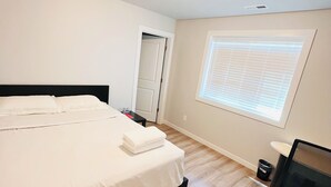 Een slaapkamer met een groot bed, een bureau en een raam met zonwering.
