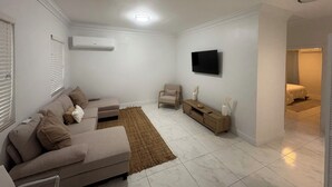 A modern living room with a sofa, a chair, a TV, and a small table. - BRAND NEW Austin Estates #3 2bed/2bath Apartment (Nassau)
