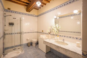 A bathroom with a glass-enclosed shower, a sink with a marble countertop, and a toilet. - La Lunaria di Lajatico (Lajatico)