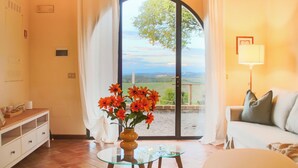 Une pièce avec une table en verre, un canapé et une vue sur l’extérieur, visible à travers une grande porte en arc de cercle.