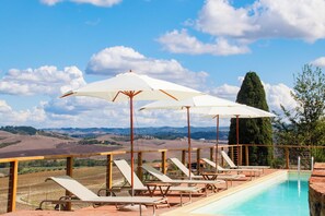 A poolside area with lounge chairs and umbrellas, overlooking a scenic landscape. - La Lunaria di Lajatico (Lajatico)