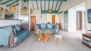 A spacious living area with a teal-colored sofa set, a glass coffee table, and a wooden side table. - Coralyne (Les Trois-Ilets)