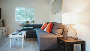 A modern living room with a grey sofa, white coffee table, and a lamp on a side table.