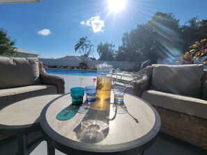 Ein Poolbereich mit Tisch, zwei Stühlen und einer großen Kanne Eistee.
