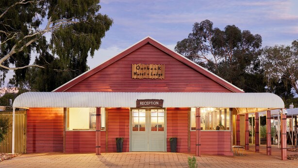 A red building with a sign reading "Olivier Hotel & Lodge" and a "Reception" sign. - Outback Lodge (Ayers Rock)