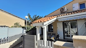 A residential property with a patio, a sliding glass door entrance, and a small outdoor seating area. - Lovely corner house,well equipped for 5 people, Airco upstairs, in a secured residence LE VILLAGE... (PORTIRAGNES)