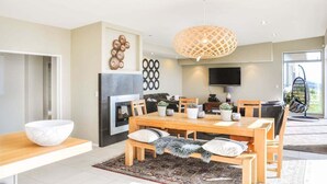 Een moderne eethoek met een houten tafel, stoelen en een grote kom op een aanrecht.
