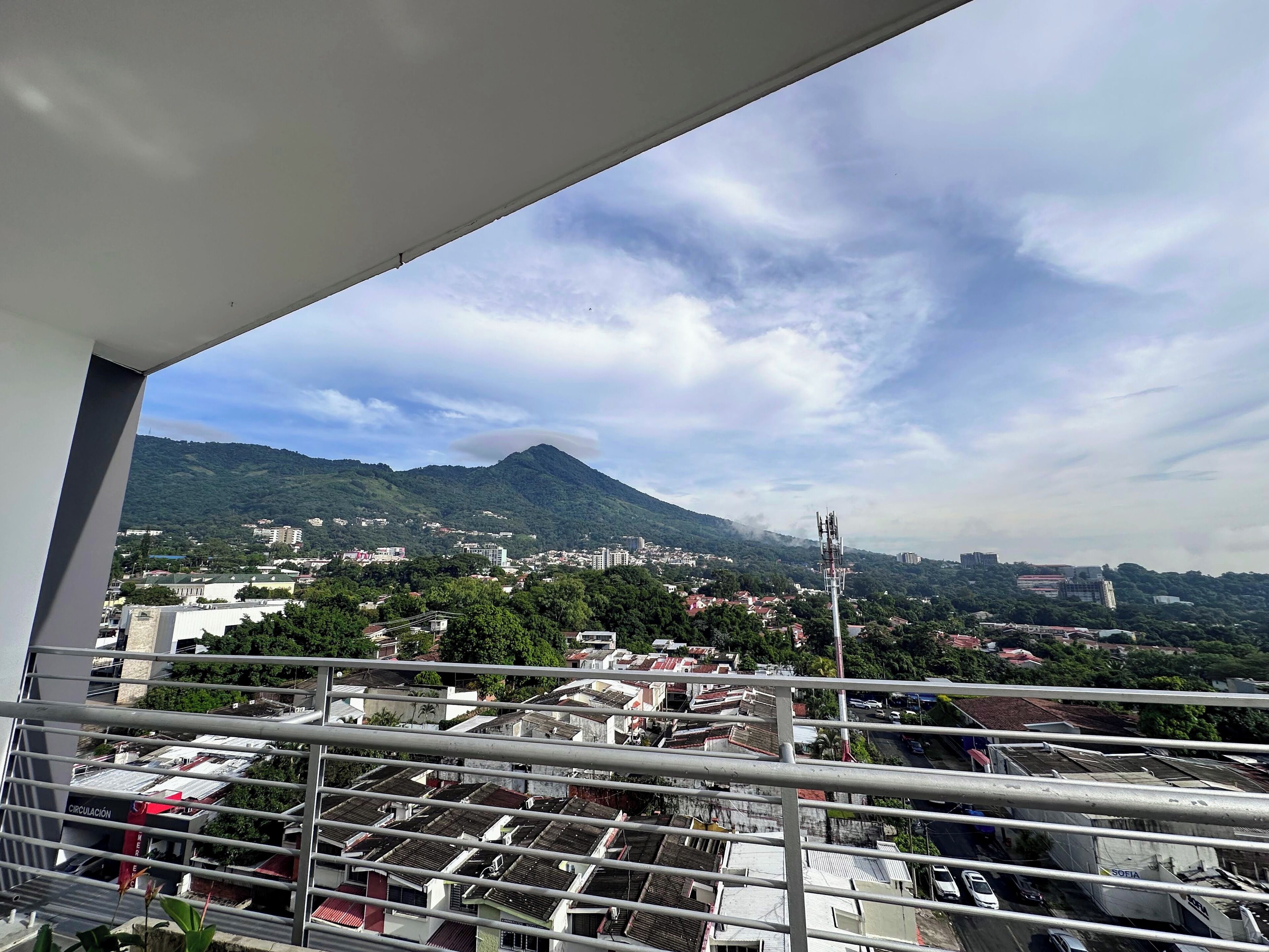 A balcony with a view of a cityscape, including buildings and a mountain.
