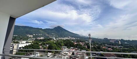 A balcony with a view of a cityscape, including buildings and a mountain.