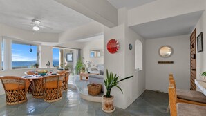 Amplia sala de estar con comedor, una planta en maceta y vista al océano.