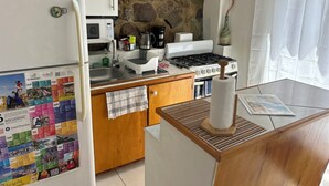Una cocina con refrigerador, microondas, estufa y un calendario en la pared.