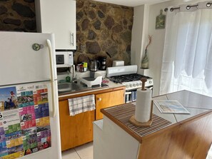 A kitchen with a refrigerator, microwave, stove, and a calendar on the wall. - Charming 1-bedroom studio in beautiful Sint Maarten. (Philipsburg)
