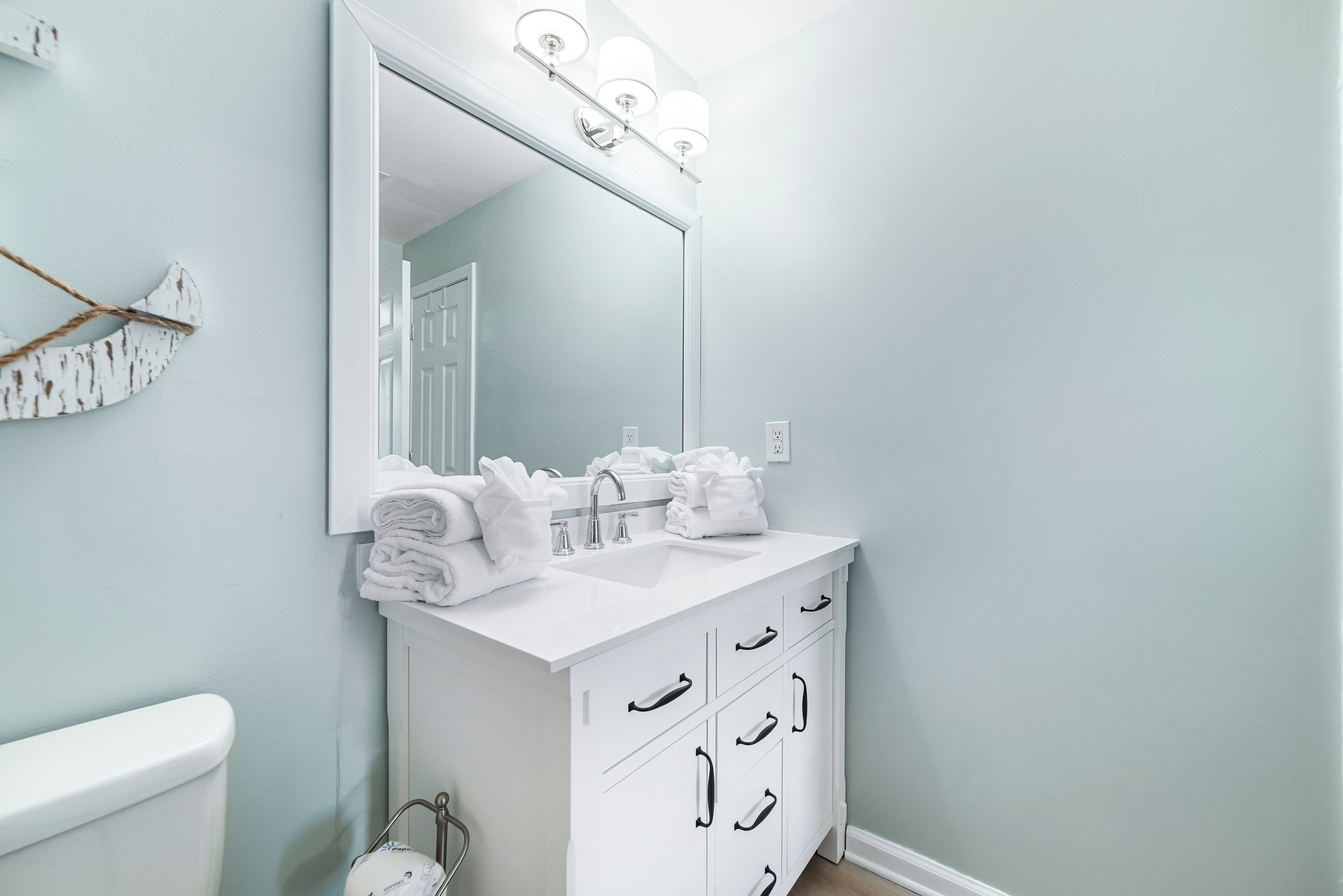 A bathroom with a white vanity, a large mirror, and a towel rack.