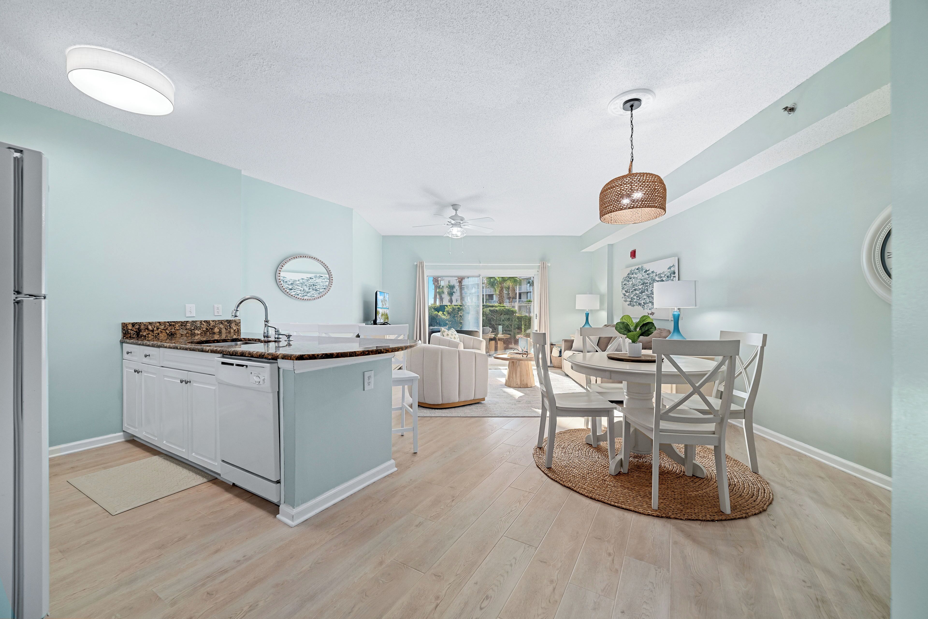 A modern kitchen with a central island, white cabinetry, and a dining area with a round table and chairs.