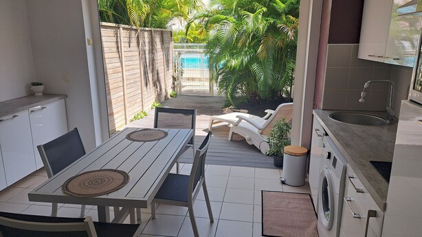 Cuina compacta amb zona de menjador, rentadora i vista a una piscina.