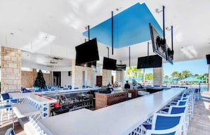 A modern bar area with a long counter, seating, and a Christmas tree. - Stitch 5-bedroom townhome 13miles from Disney Parks (Clermont)