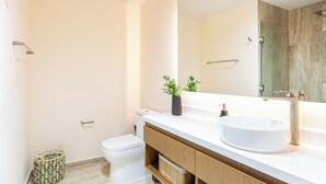 Een moderne badkamer met een wit wastafelmeubel, een spiegel en een houten wastafel.